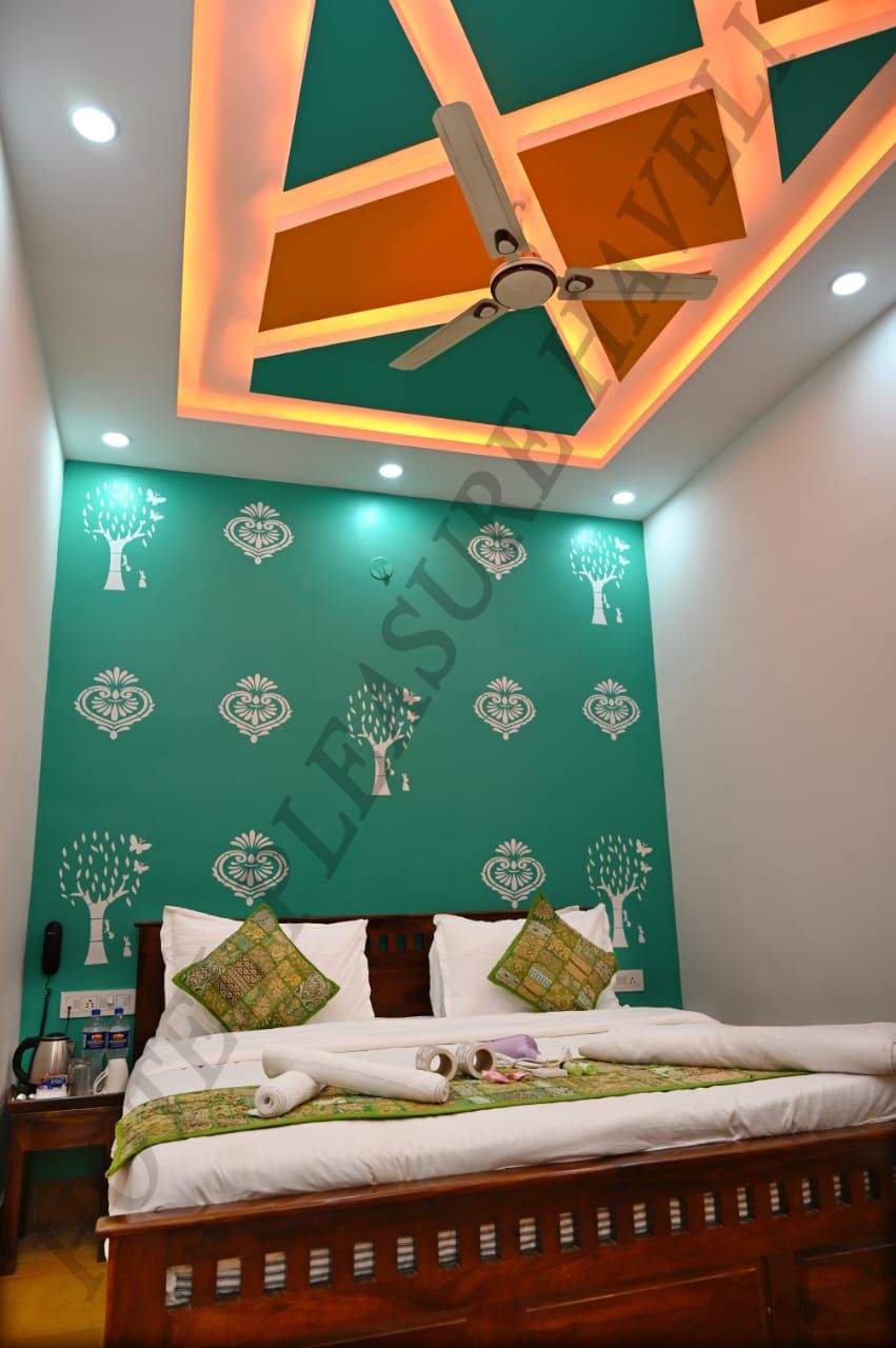 A bedroom with a bed, a ceiling fan, and a green wall with tree patterns.