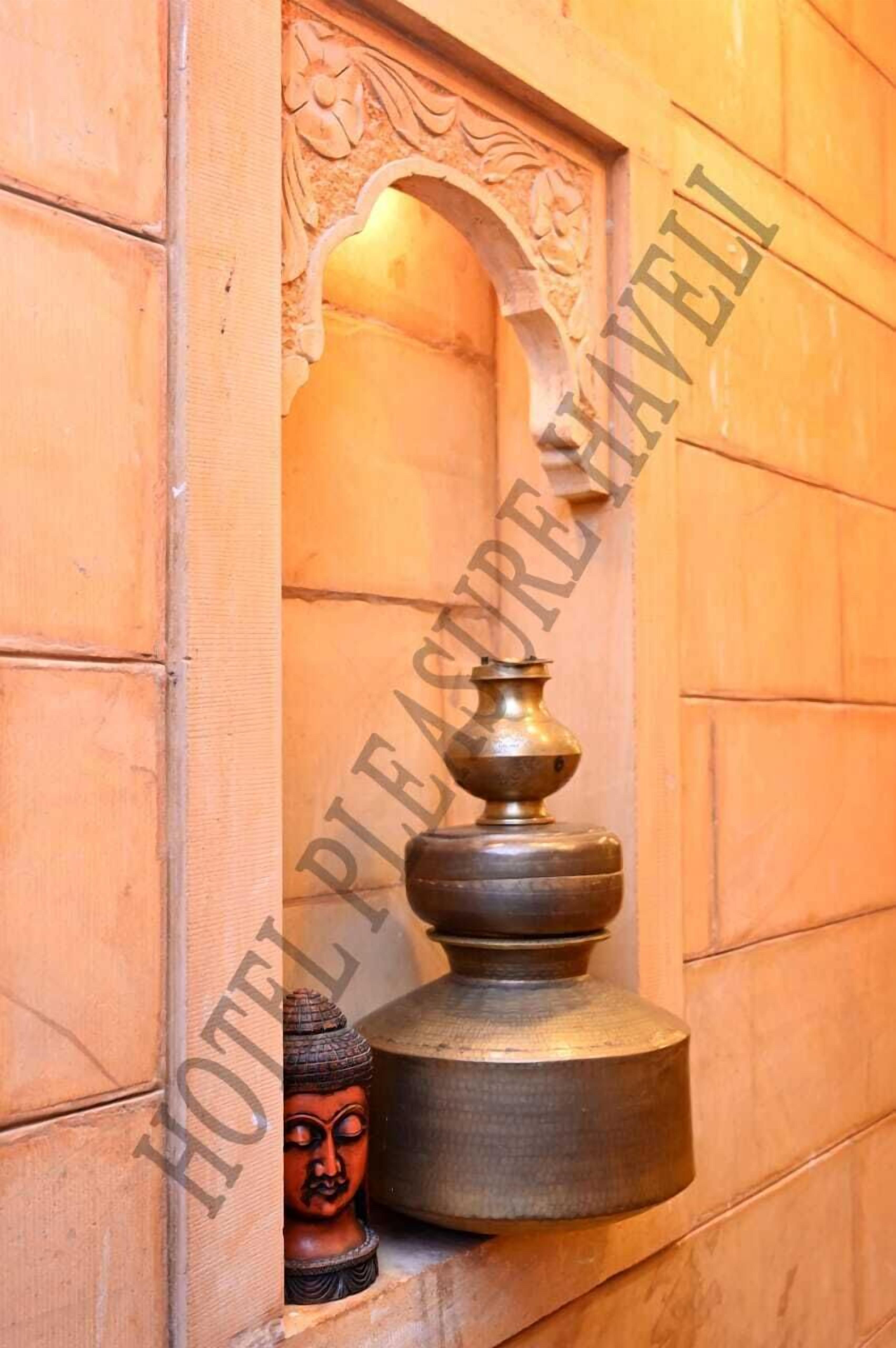 A traditional wooden wall with a decorative niche containing a Buddha statue and a brass object.