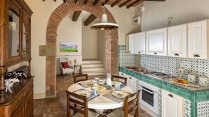 A traditional kitchen with a brick archway, white cabinets, and a tiled backsplash. - Elegant historic residence in the hills of Val d'Orcia (Montepulciano)