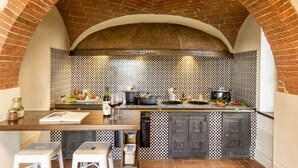 A kitchen with a brick archway, checkered backsplash, and a wooden countertop with cooking utensils. - Elegant historic residence in the hills of Val d'Orcia (Montepulciano)