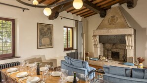 A dining area with a wooden table set for a meal, a fireplace, and blue sofas. - Elegant historic residence in the hills of Val d'Orcia (Montepulciano)