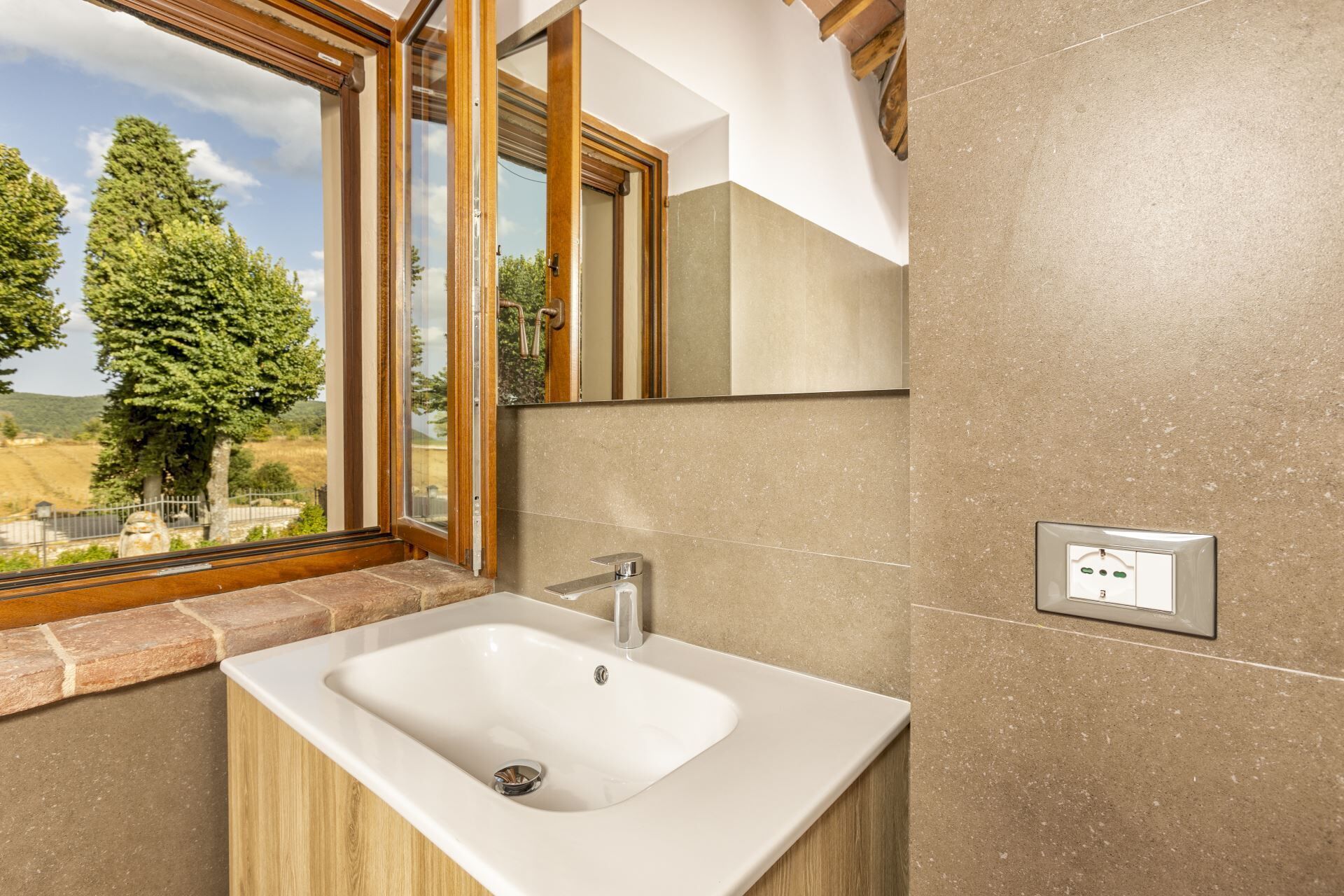 Une salle de bain équipée d’un lavabo, d’une fenêtre et d’un interrupteur fixé au mur.
