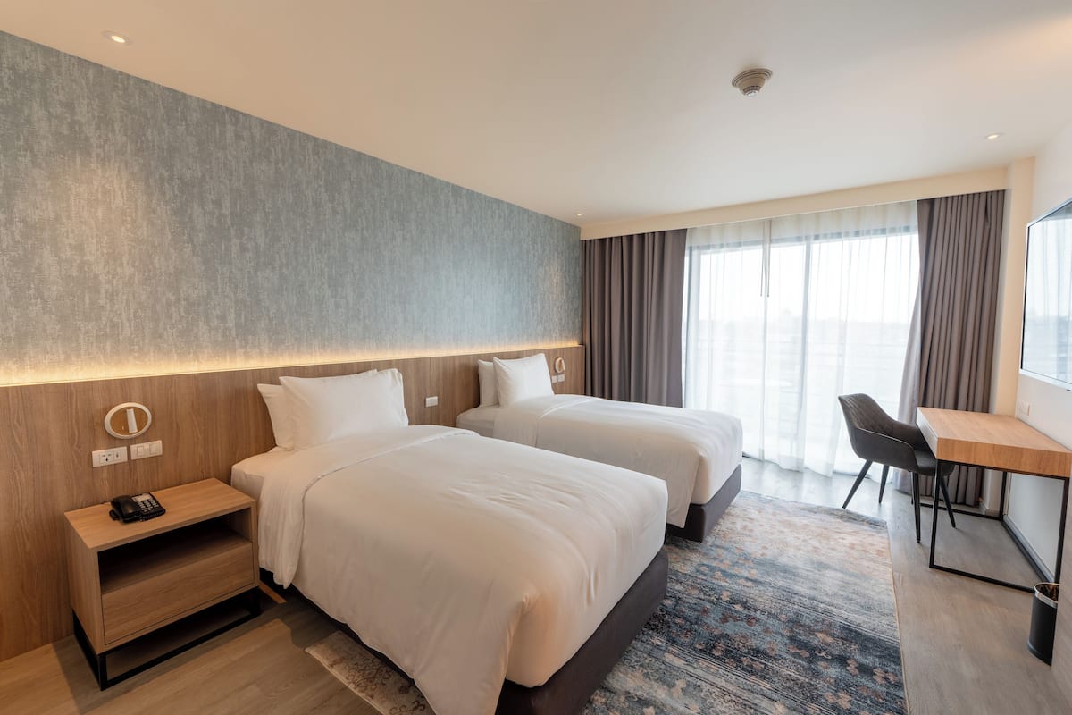 A hotel room with two beds, a desk, and a chair.