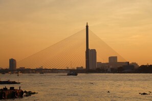 A cable-stayed bridge with multiple cables, a tall central tower, and a city skyline in the background.