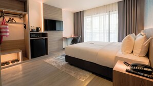 A modern hotel room with a large bed, a desk, a television, and a kitchenette. - TARA Bangkok Riverside (Formerly GLOW Bangkok Riverside) (Bangkok)