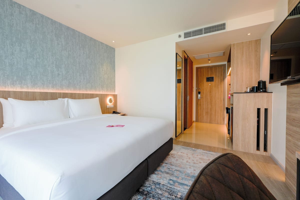 A modern hotel room with a large bed, a desk, and a television.