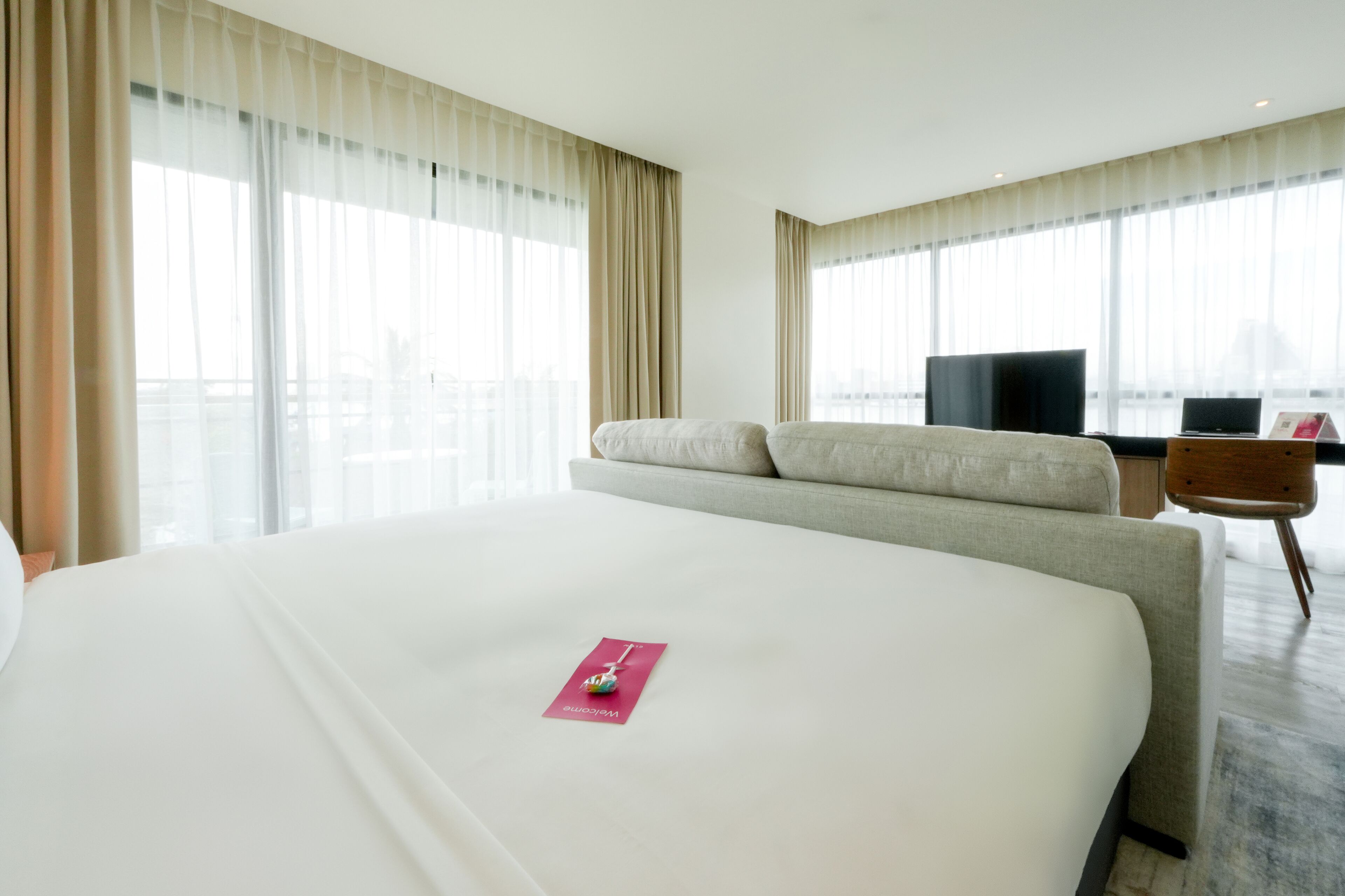 Habitación de hotel con una cama grande, televisión, escritorio y vistas a la ciudad.