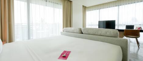 Habitación de hotel con una cama grande, televisión, escritorio y vistas a la ciudad.
