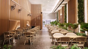 A long, narrow indoor space with rows of wicker tables and chairs, wooden slats on the walls, and potted plants along the right side. - TARA Bangkok Riverside (Formerly GLOW Bangkok Riverside) (Bangkok)