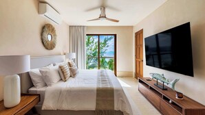 Ein Schlafzimmer mit Bett, Deckenventilator, Fernseher, Fenster mit Blick und einem Nachttisch aus Holz.
