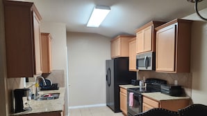 Una cocina con armarios de madera, un refrigerador, un microondas, una estufa y un lavabo.