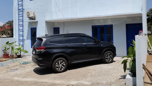 Un immeuble de deux étages devant lequel est garé un SUV noir.