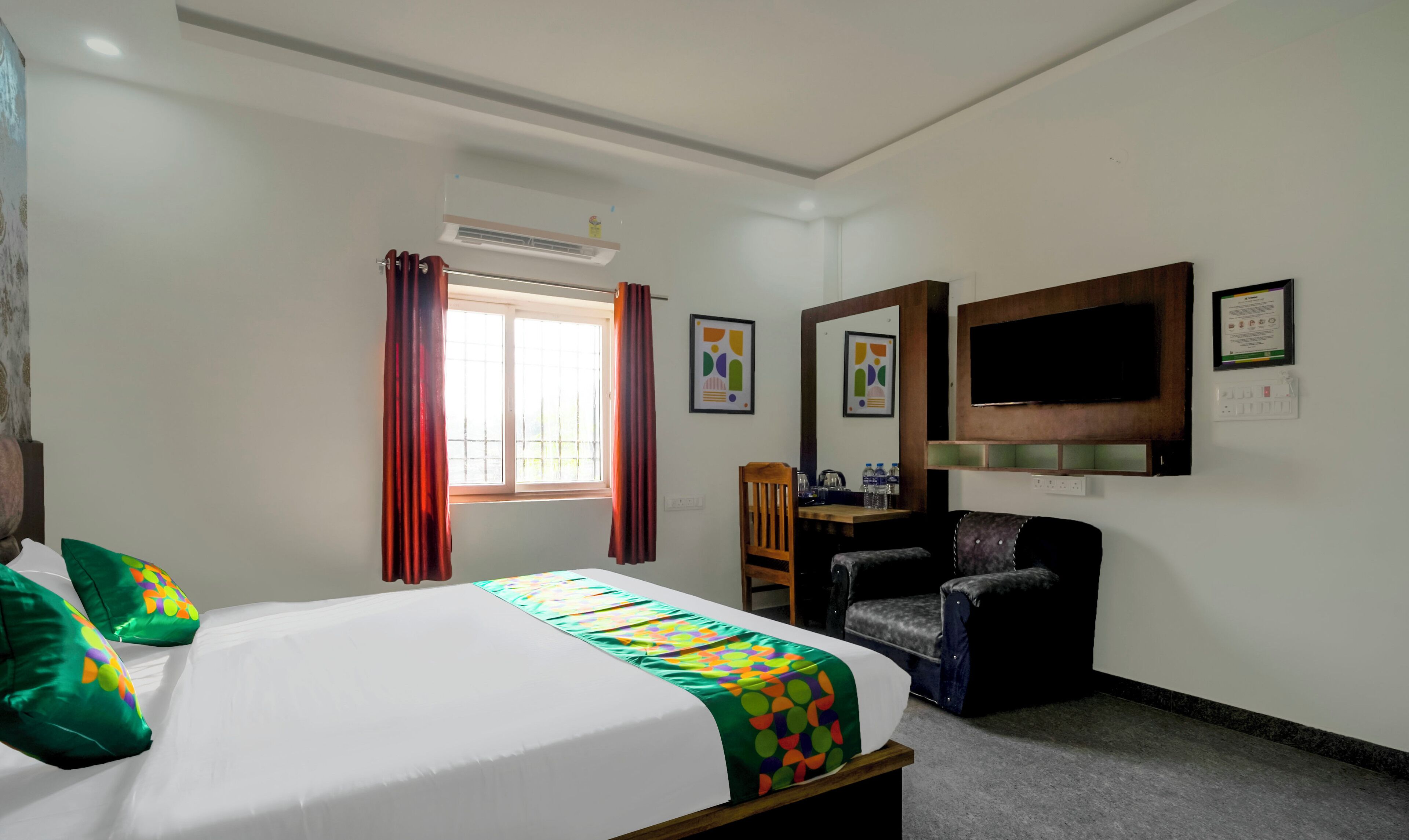 A hotel room with a bed, a desk, a chair, a TV, and a window with curtains.