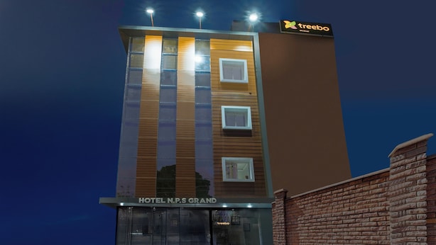 En modern hotellbyggnad med en skylt som visar texten ”HOTEL N.P.S GRAND” och en ”treebo”-skylt högst upp.