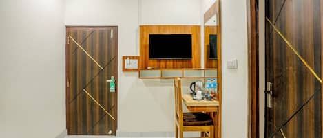 A bedroom with a bed, a desk with a chair, a television, and a wardrobe.