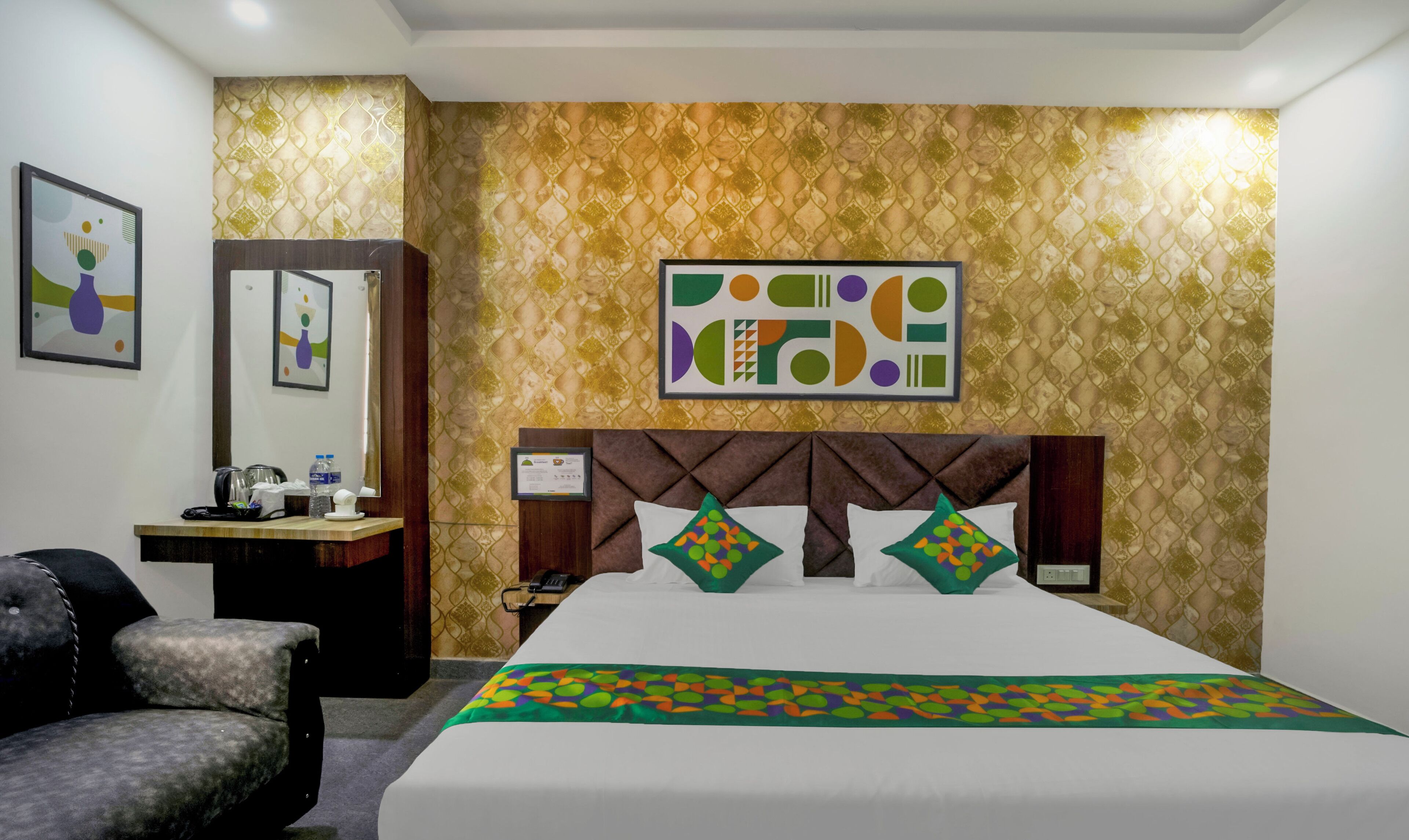 A hotel room with a bed, a desk, a chair, and a wall with a geometric pattern.