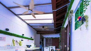A compact living space with a blue sofa, a ceiling fan, a washing machine, and a small kitchen area. - Coller Chinatown (Singapore)