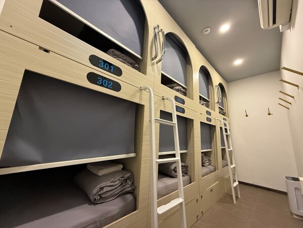Bunk beds with numbers, a white trash bin, and a ceiling light. - Coller Chinatown (Singapore)