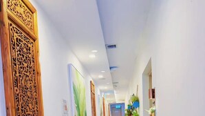 A hallway with a wooden door on the left, a trash bin, and a staircase leading to an upper floor. - Coller Chinatown (Singapore)