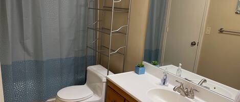 A bathroom with a toilet, sink, and shower curtain.