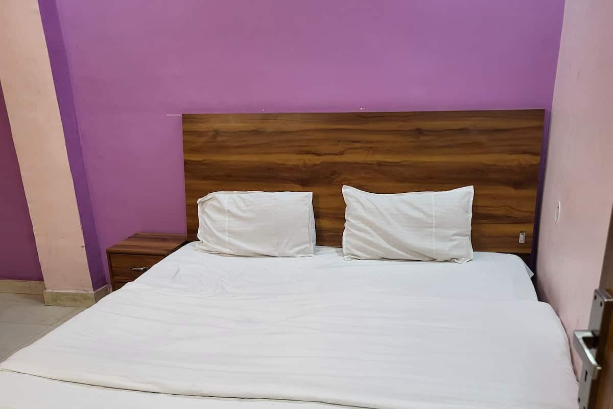 Una cama con cabecera de madera en una habitación con paredes moradas.