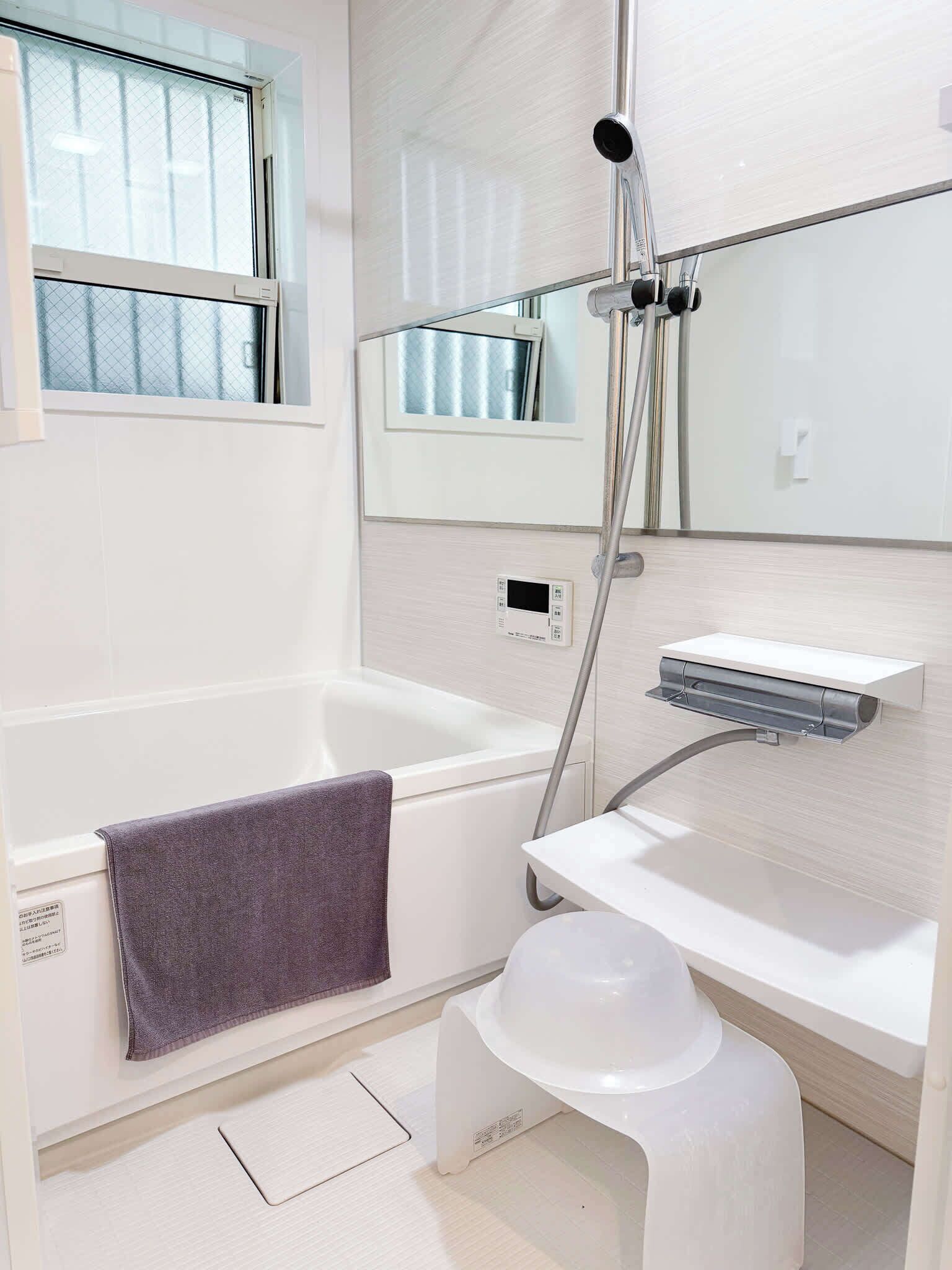 Un baño moderno con bañera, ducha, toallero y un taburete pequeño.