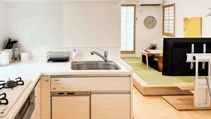 A modern kitchen with a dishwasher, sink, and stove. There is a dining area with a table and chairs, and a small plant on the table.