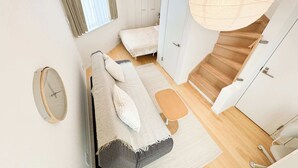 A room with a sofa, a small table, a mirror, and a large hanging light fixture.