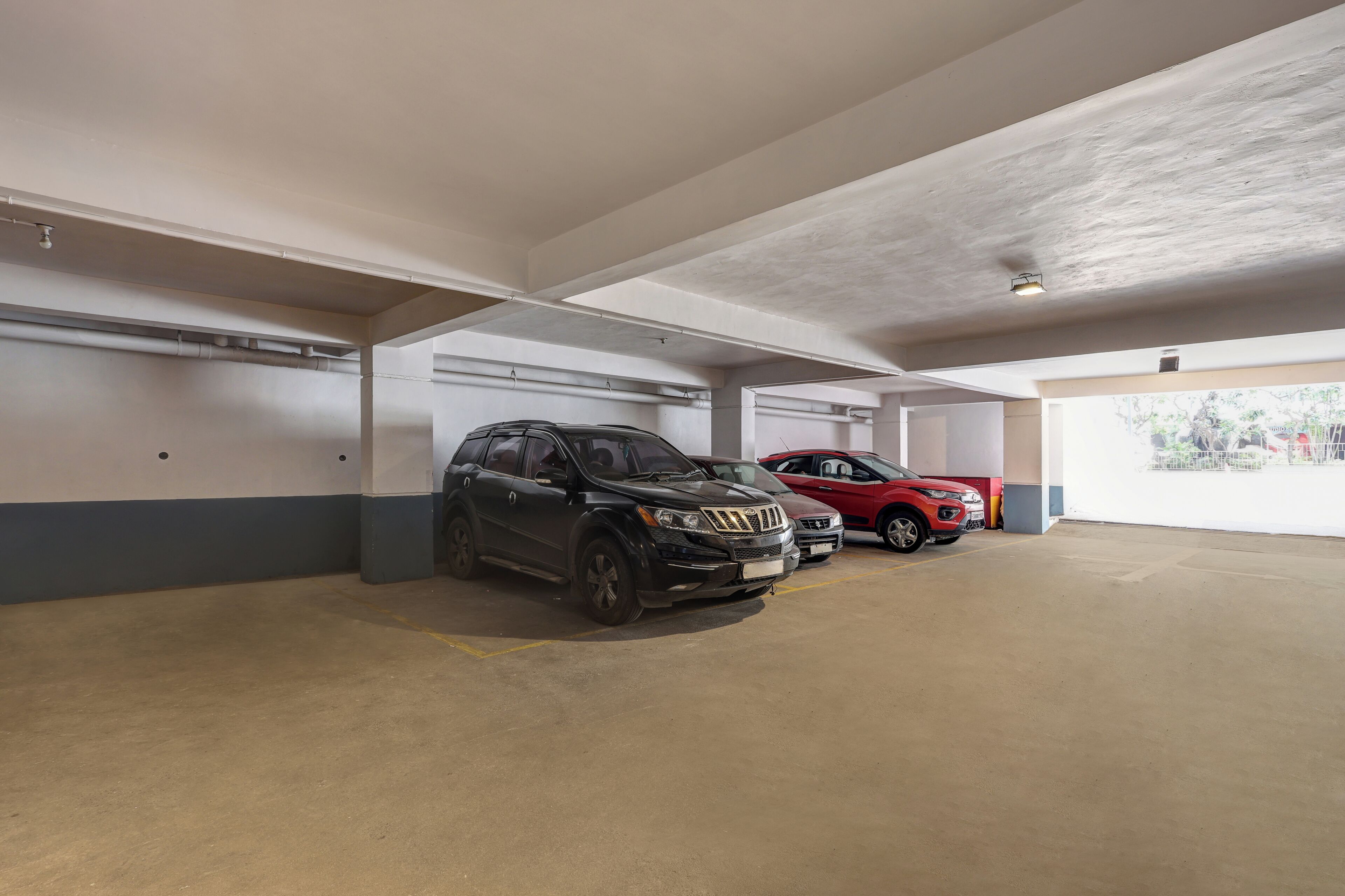 A parking garage with two cars parked in adjacent spaces.