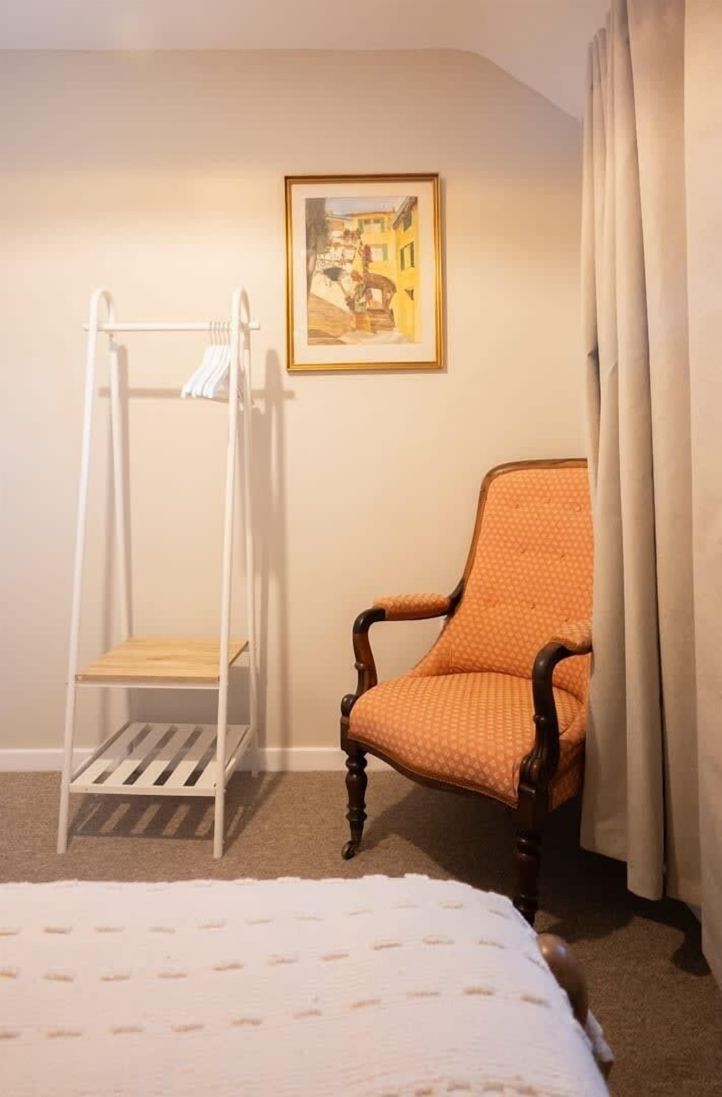 Una habitación con una cama litera, una silla, un cuadro en la pared y una cortina.