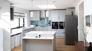 Une cuisine moderne avec des meubles blancs, un îlot central et un grand réfrigérateur.