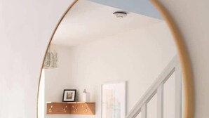 Un miroir rond avec un cadre en bois, accroché au mur.