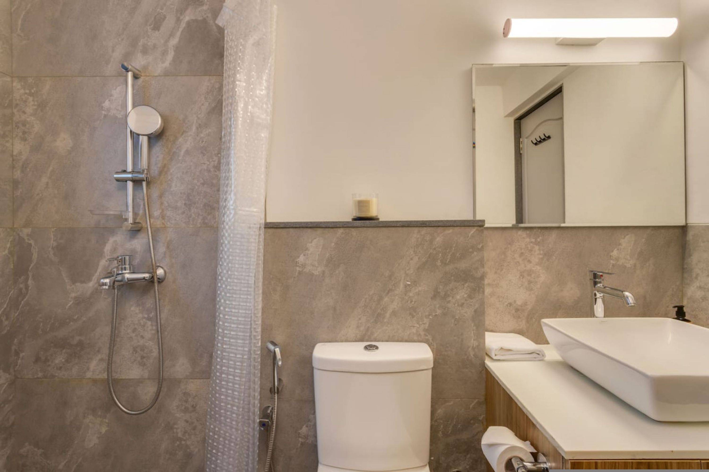 Een moderne badkamer met douche, toilet, wastafel en spiegel.
