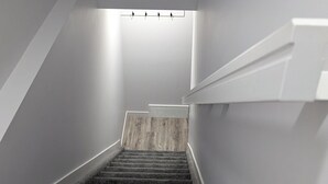 A staircase with carpeted steps leading up to a landing with a light fixture. - President's Choice: Spacious 1-Bedroom Basement Suite with Fireplace (Edmonton)