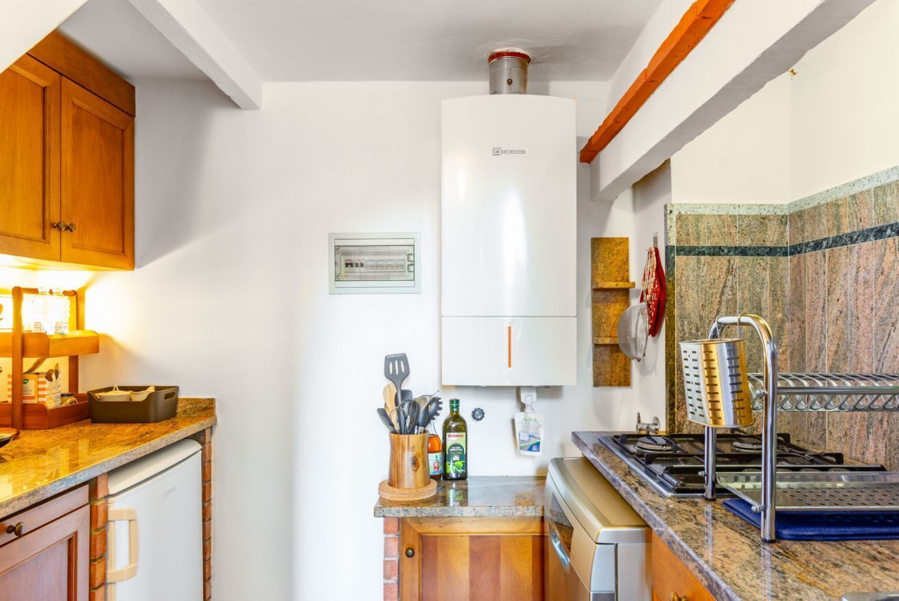 A kitchen with a white refrigerator, wooden cabinets, a stove, and a tiled backsplash.