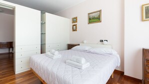 Ein Schlafzimmer mit Bett, Kleiderschrank, Nachttisch und Spiegel.