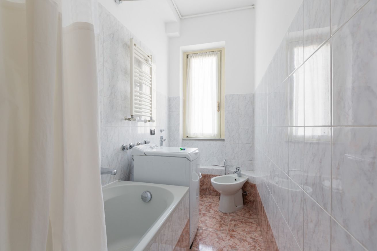 Un baño con bañera, lavamanos y ventana.