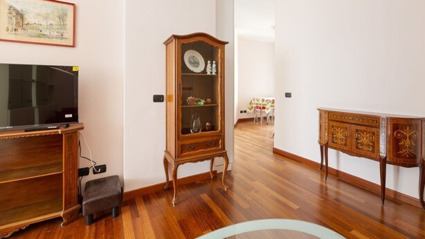 Ein Zimmer mit einem Holzschrank, einem Fernseher und einem Essbereich mit Tisch und Stühlen.