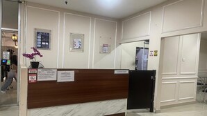 A hotel reception area with a marble counter, a black refrigerator, and several informational signs on the walls. - Hotel O Grand Asia Afrika Apartment By Qr Property (Bandung)