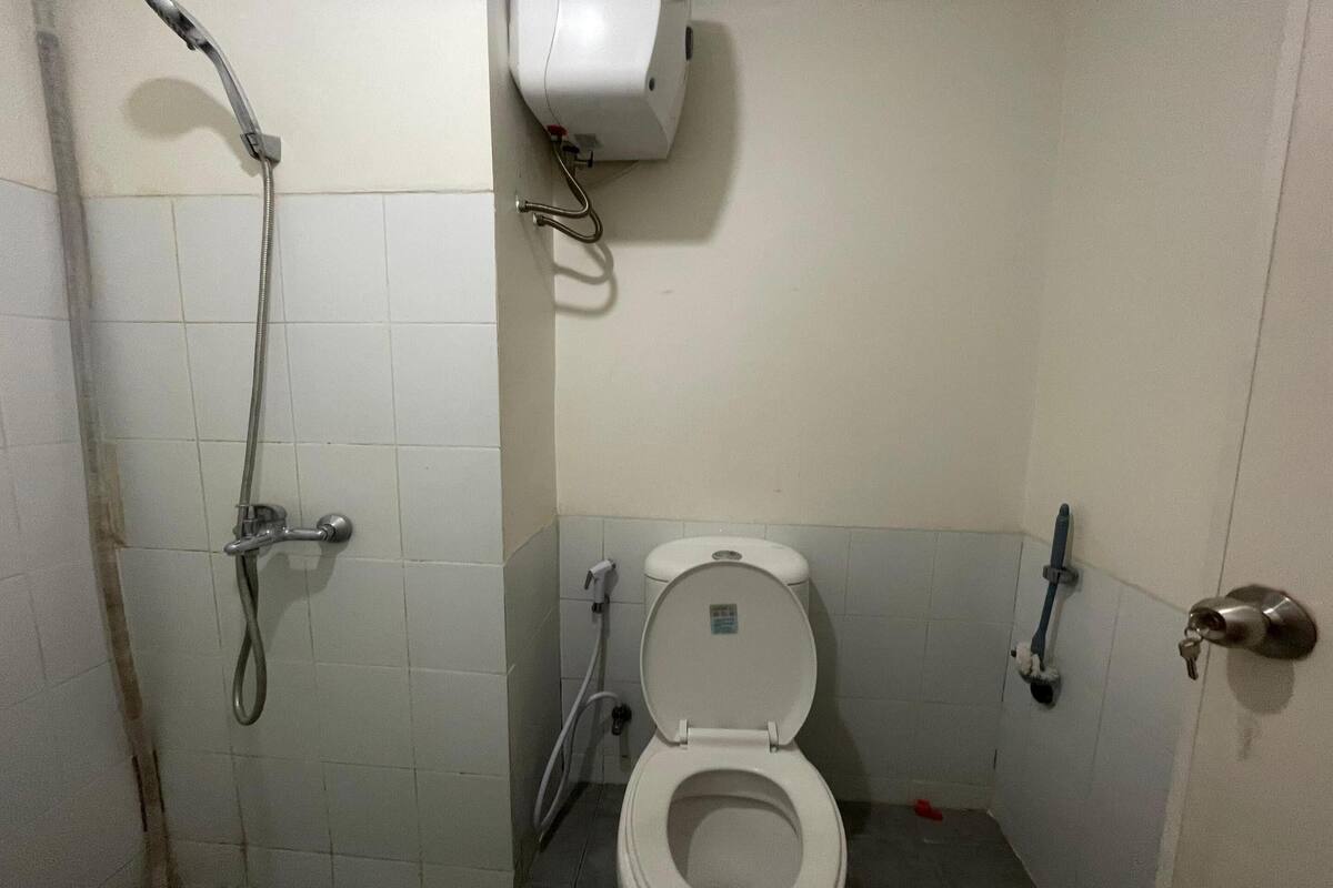 Une petite salle de bain équipée de toilettes, d’un sèche-mains et d’un pommeau de douche.
