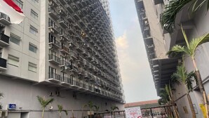A multi-story residential building with balconies, a mural, and a bus stop. - Hotel O Grand Asia Afrika Apartment By Qr Property (Bandung)