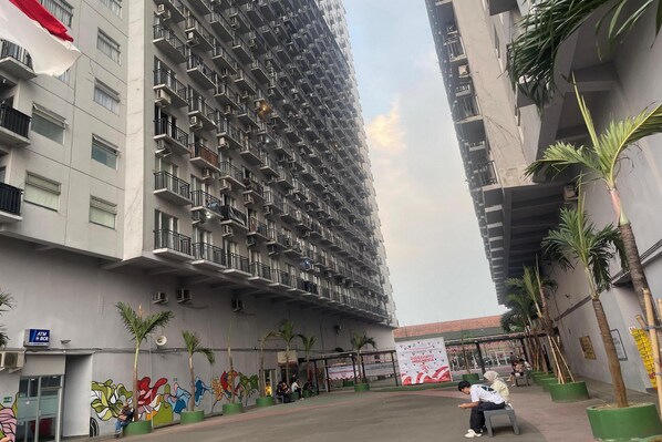 A multi-story residential building with balconies, a mural, and a bus stop. - Hotel O Grand Asia Afrika Apartment By Qr Property (Bandung)