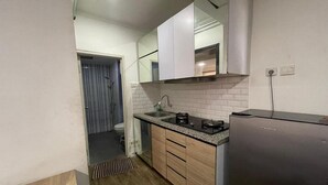 A compact kitchen with a sink, stove, and a refrigerator. - Hotel O Grand Asia Afrika Apartment By Qr Property (Bandung)