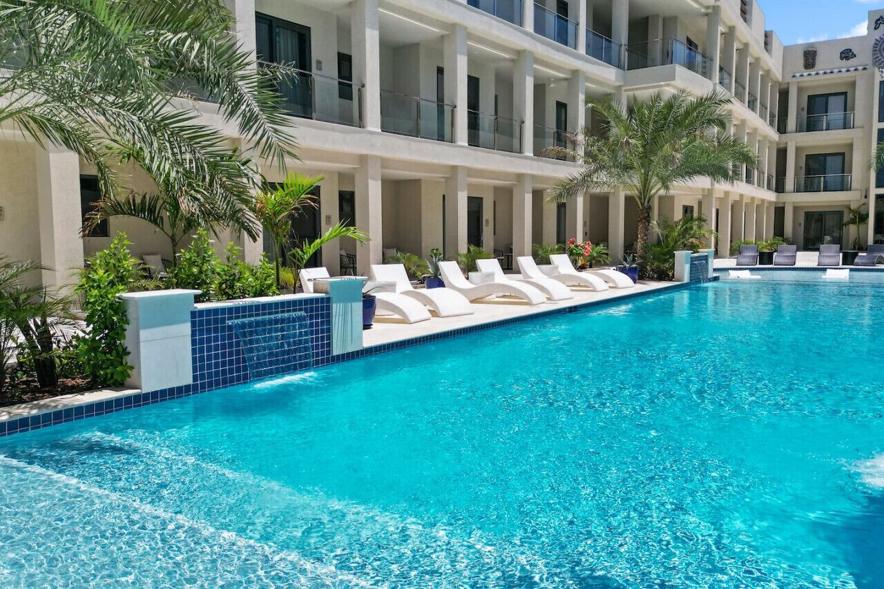 Un espace piscine avec des chaises longues et des palmiers.
