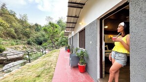 A woman standing at the entrance of a building with a red-tiled walkway leading to a door. - Anandvan Jungle Resort (Rishikesh)