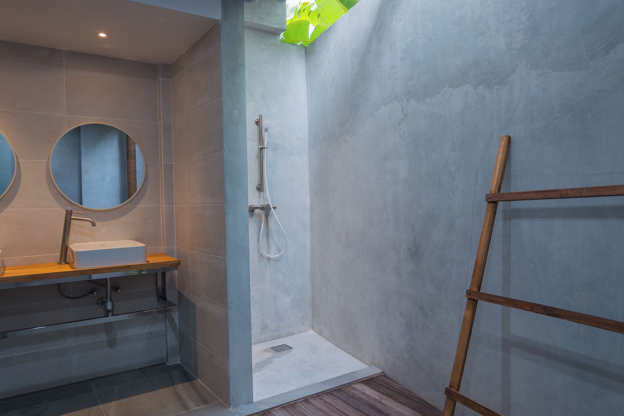 A modern bathroom with a shower, a sink with a mirror, and a wooden shelf.