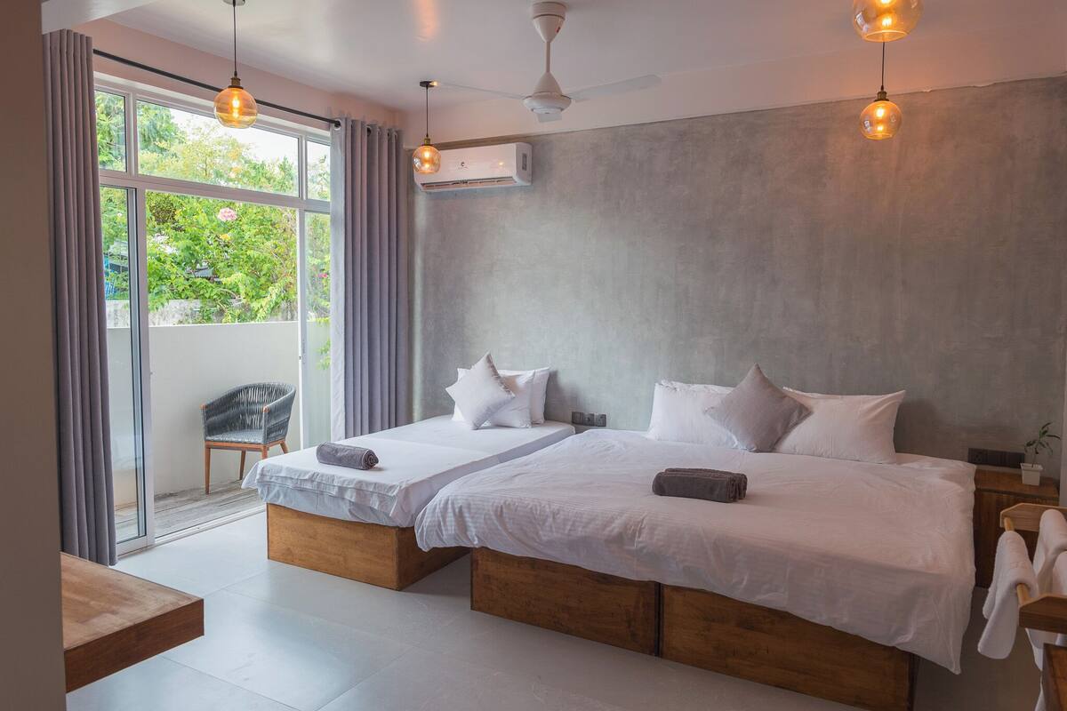 A modern bedroom with two beds, a large window, and an air conditioning unit.