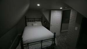 Un dormitorio con cama, una puerta y una lámpara.