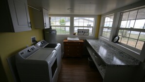 Cocina compacta con lavadora y secadora integradas, armarios de madera, encimera de granito y ventana con vistas al patio trasero.
