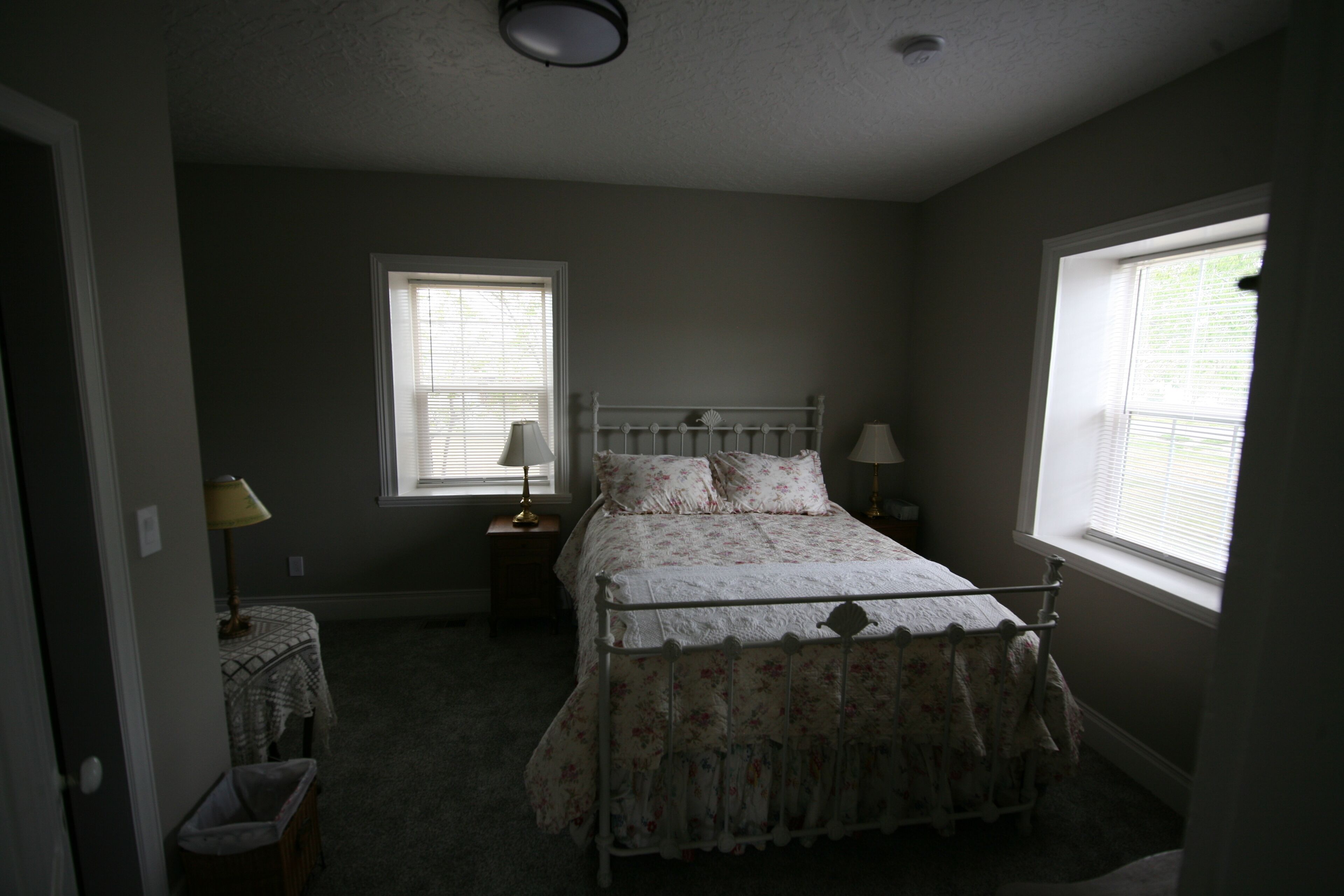 A bedroom with a bed, two bedside tables, a nightstand, a window, and a door.